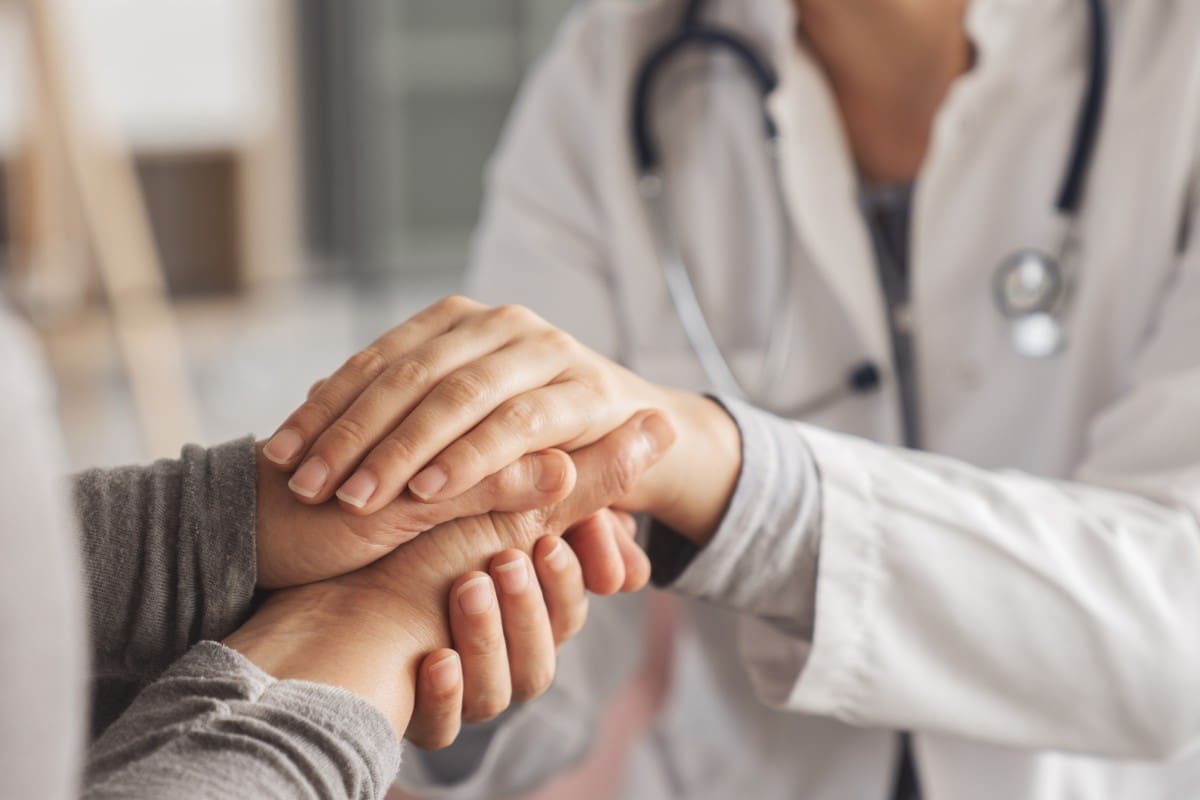 Doctor comforting patient by holding hands.