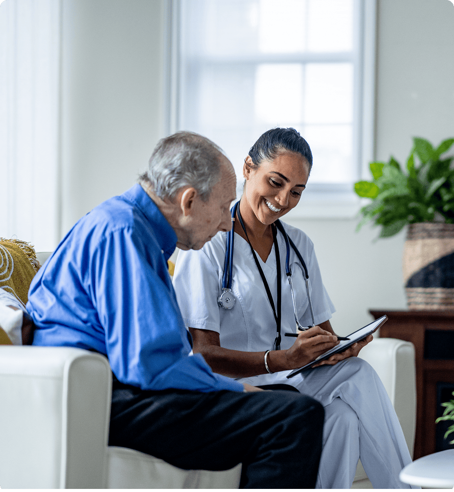 Nurse discussing with elderly man at home.