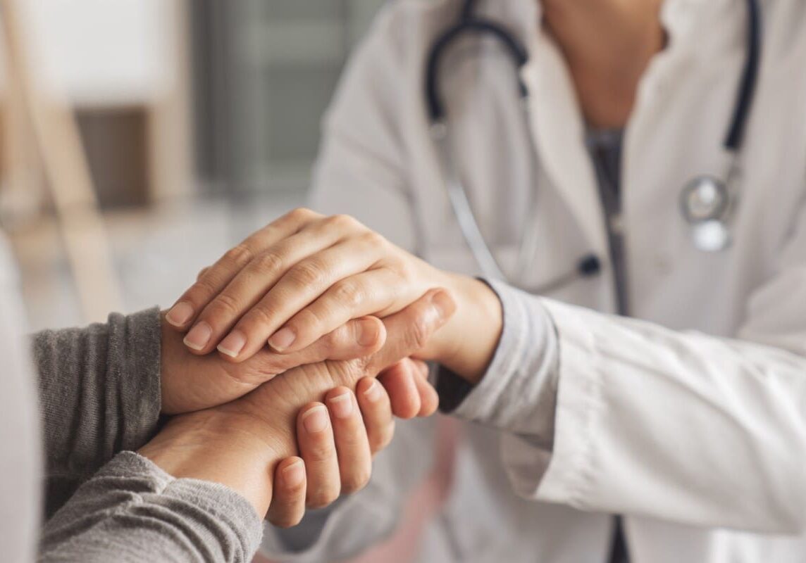 Doctor comforting patient by holding hands.